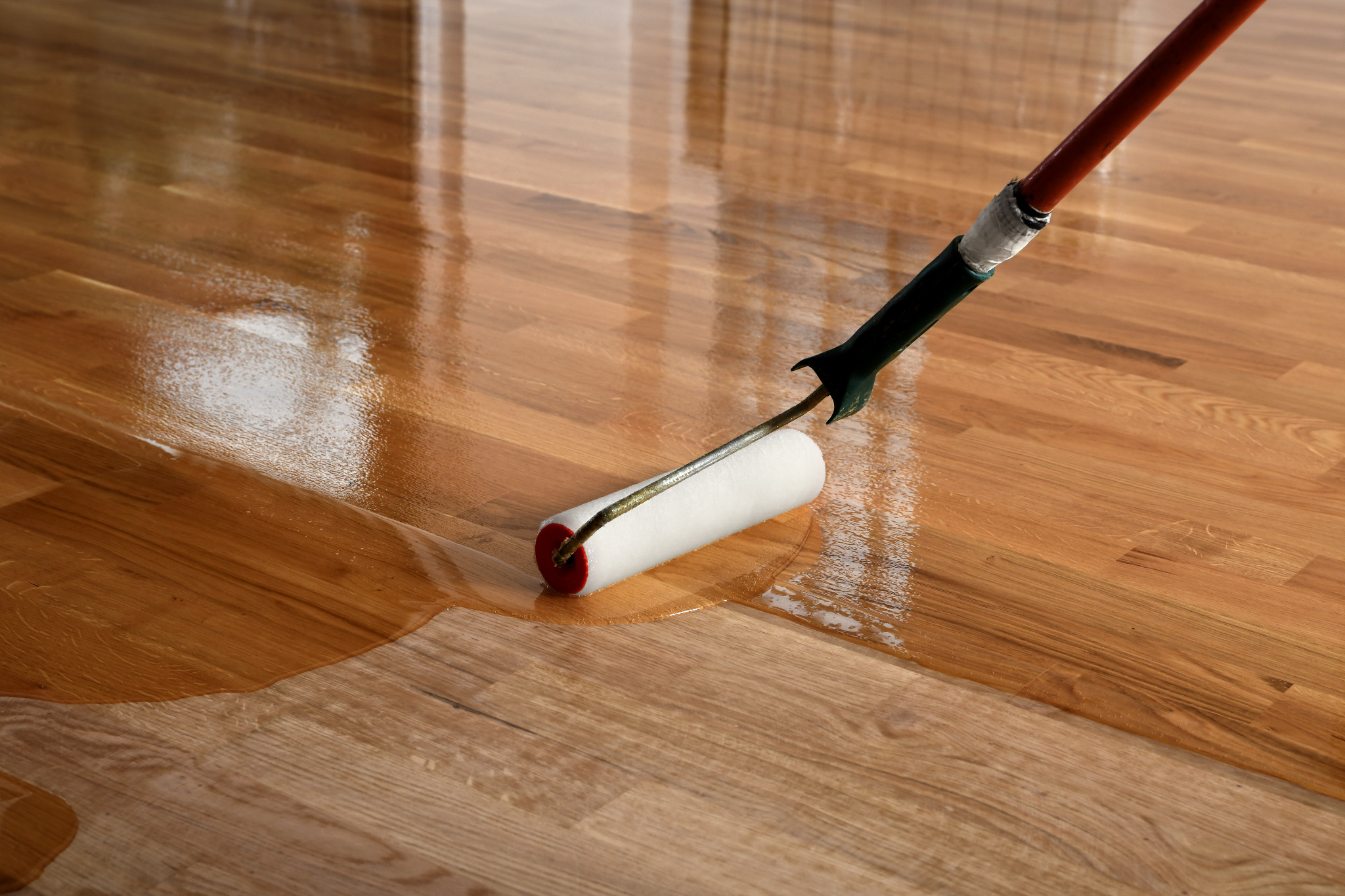 Restaurant Floor Sanding in Honoroak—roller applying a clear coat to a freshly sanded oak hardwood plank floor, showing a smooth wet edge in the dining area.