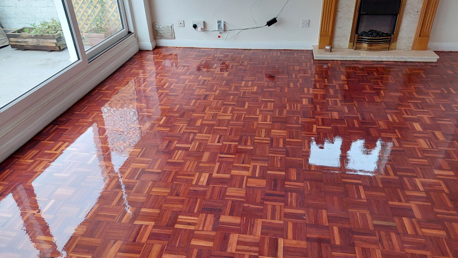Wood Floor Sanding in Honor Oak on a hardwood mosaic parquet block floor, fully restored to a rich high-gloss finish in a living room.
