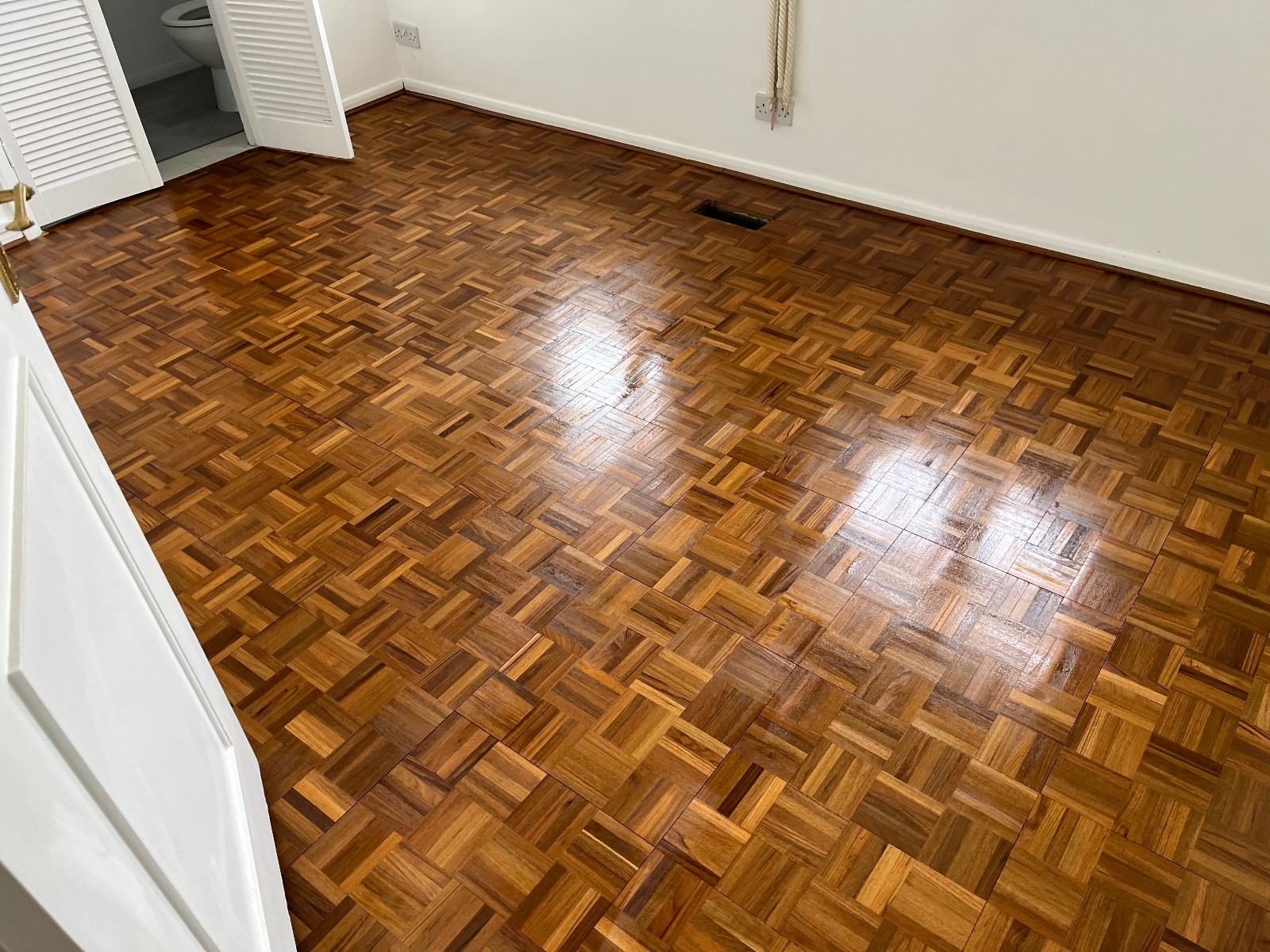Wood Floor Sanding in Honor Oak on a hardwood mosaic parquet block bedroom floor, fully restored to a smooth, glossy finish.