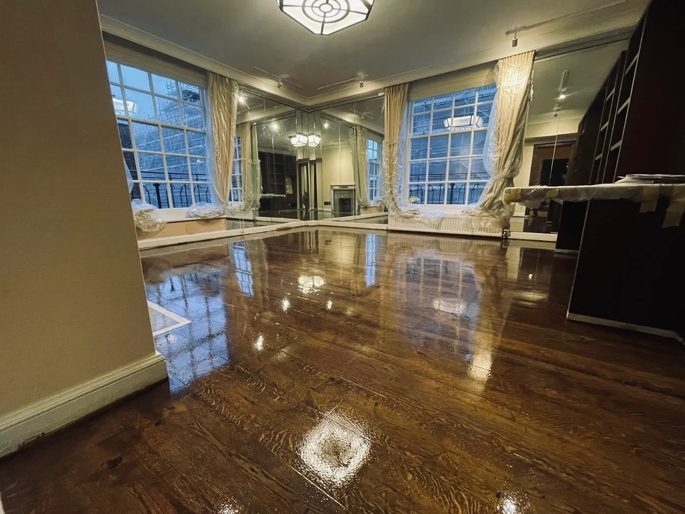 Commercial Floor Sanding in Honor Oak – dark oak hardwood plank floor in a luxury commercial room, freshly sanded and lacquered to a deep, glossy finish.