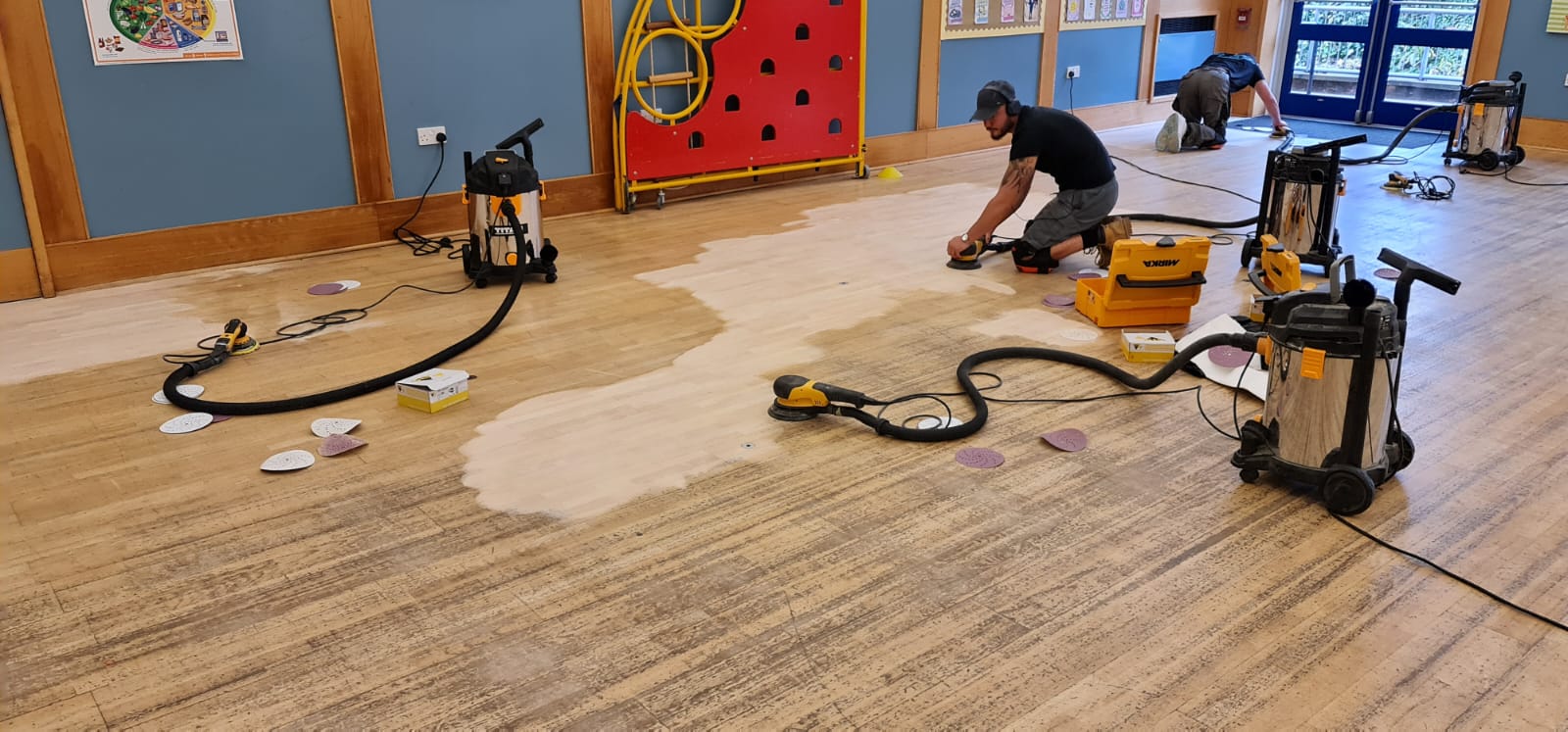 Commercial Floor Sanding in Honor Oak – maple hardwood school hall floor being sanded with dust-free machines, showing worn boards turning into clean, smooth timber.