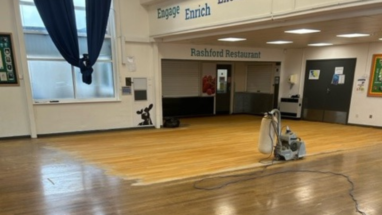 Commercial Floor Sanding in Honor Oak – oak hardwood school hall and dining area mid-sanding, showing the transformation from dark, worn boards to fresh, clean timber.
