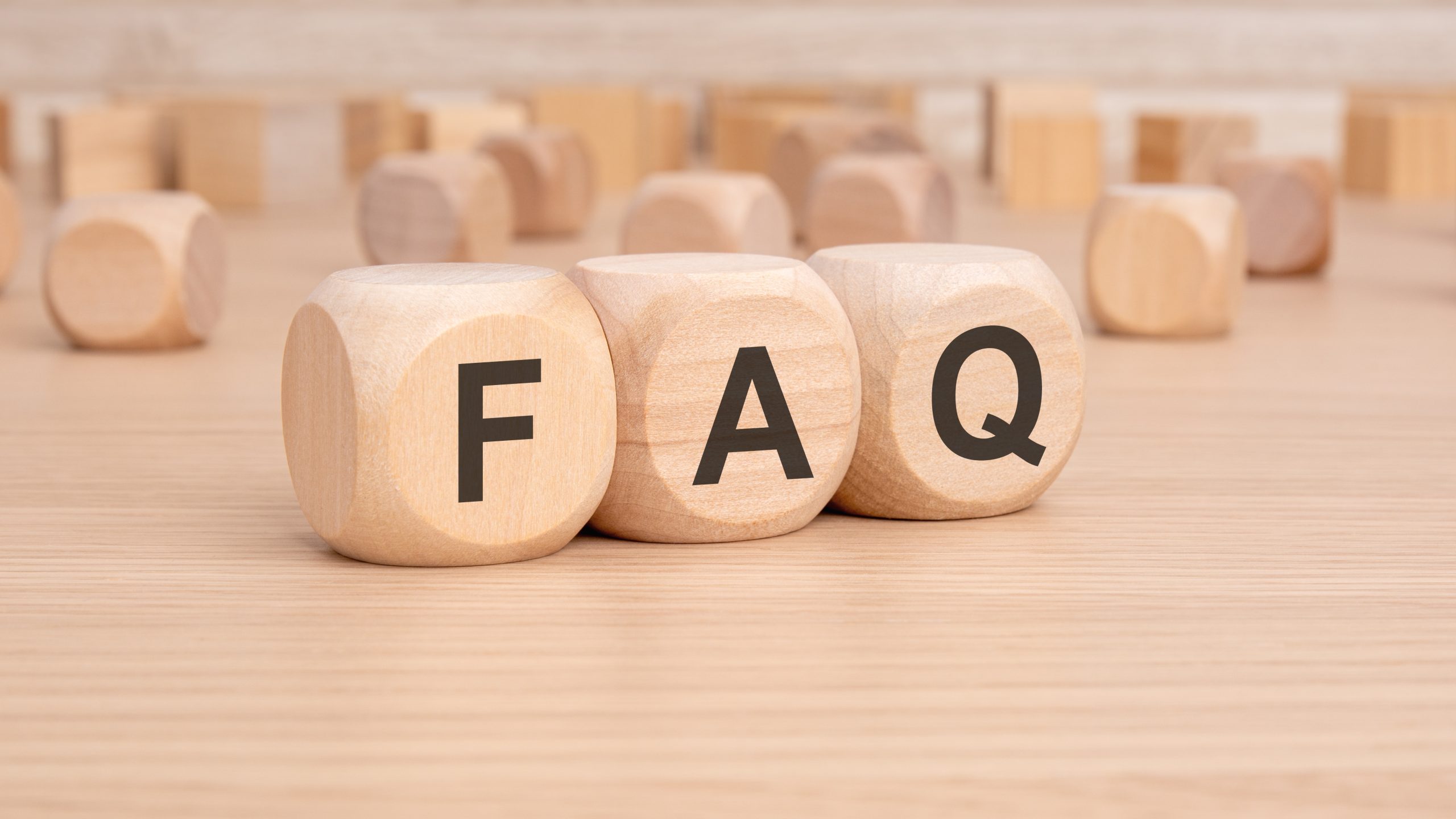 Commercial Floor Sanding in Honor Oak – FAQ text on wooden blocks sitting on an oak plank hardwood floor, introducing common questions about commercial floor sanding services.