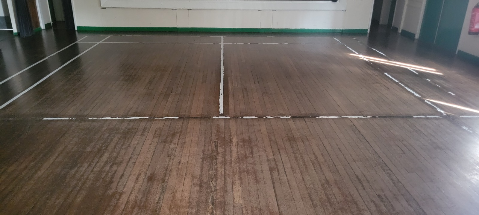 Commercial Floor Sanding in Honor Oak – worn maple strip hardwood hall floor with faded sports court lines awaiting restoration.
